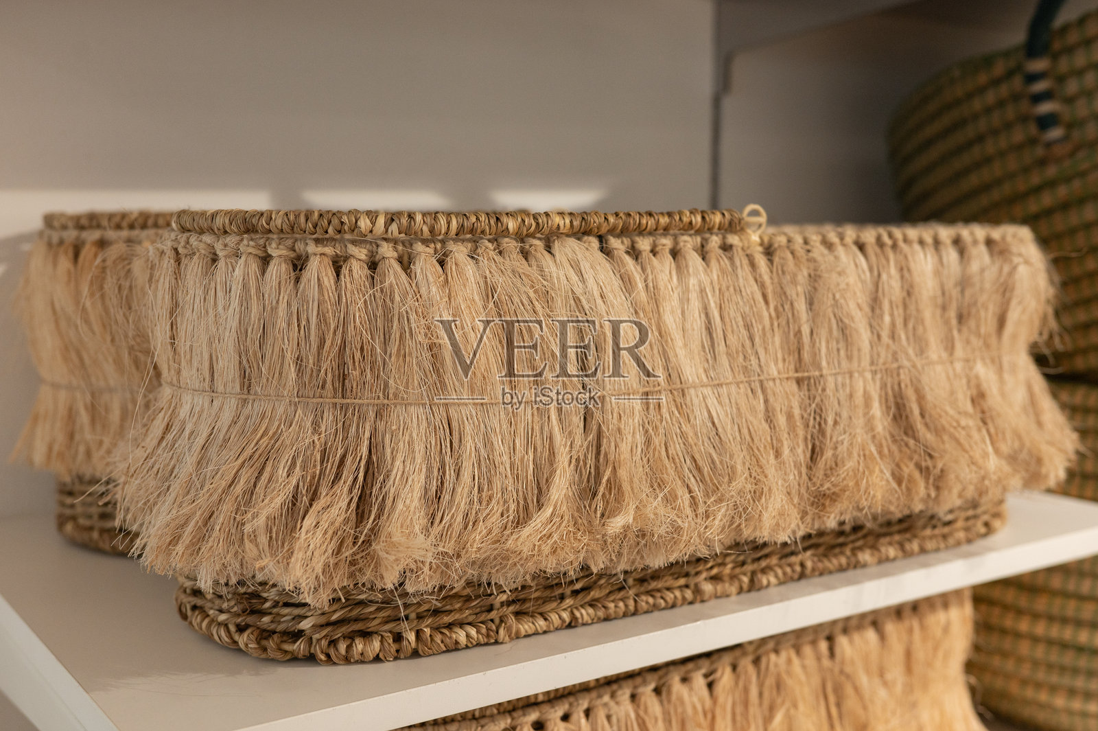 白色架子上的手工编织流苏篮子，具有纤维纹理和自然设计照片摄影图片