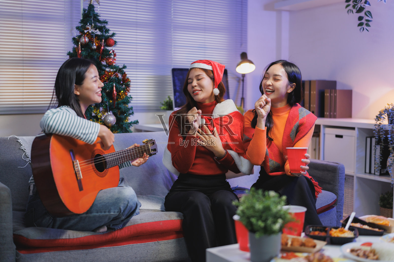 一群亚洲朋友在家开派对，弹着吉他唱圣诞颂歌。照片摄影图片