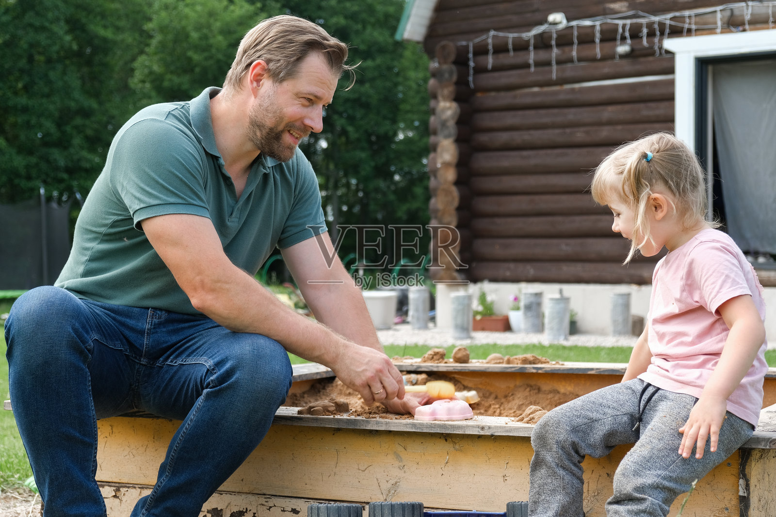 快乐的父亲在户外与女儿玩耍。四岁小女孩对着爸爸微笑、抬头。男人对孩子示爱。真实的情感瞬间。留胡子的爸爸和小孩。真实的家庭。照片摄影图片