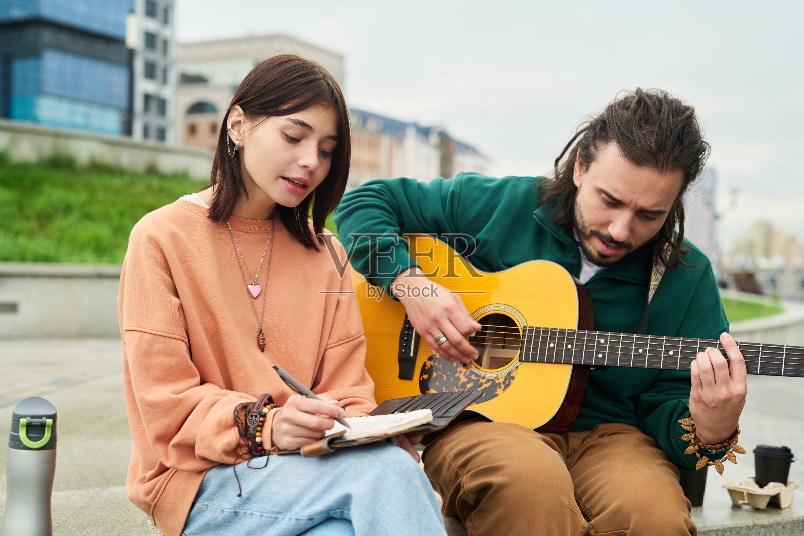 年轻的白人女子在写歌词，年轻的白人男子在弹吉他照片摄影图片
