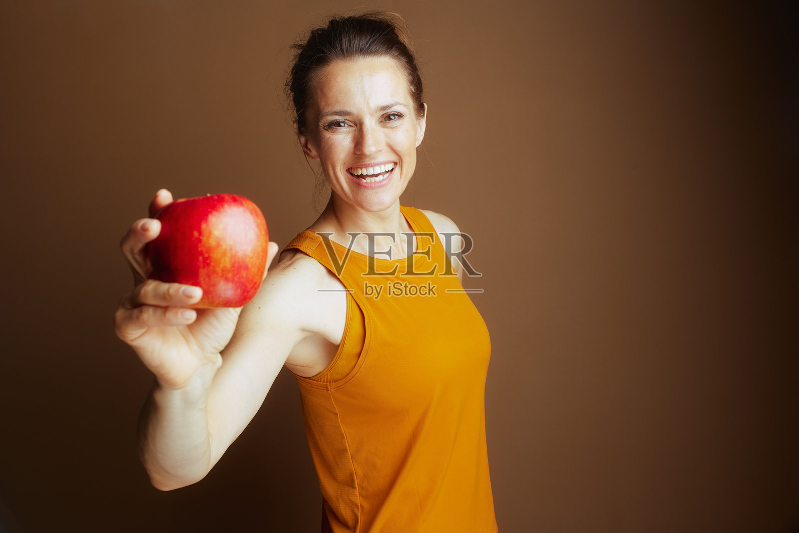平易近人的女士递上一颗健康的红苹果照片摄影图片