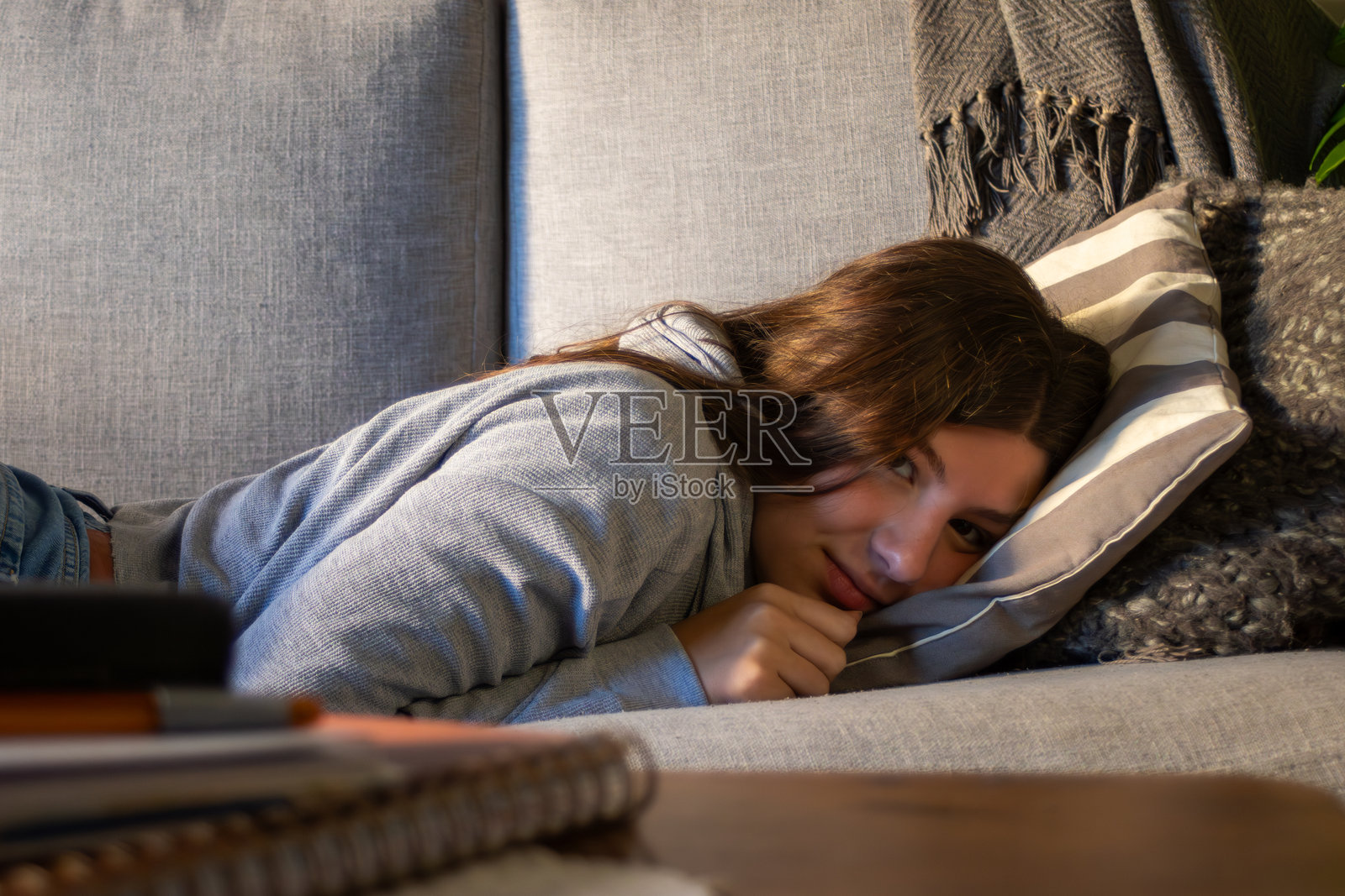 一个漂亮的金发少女放松地靠在沙发上，居家休闲，展现现代年轻人的生活方式，照片摄影图片