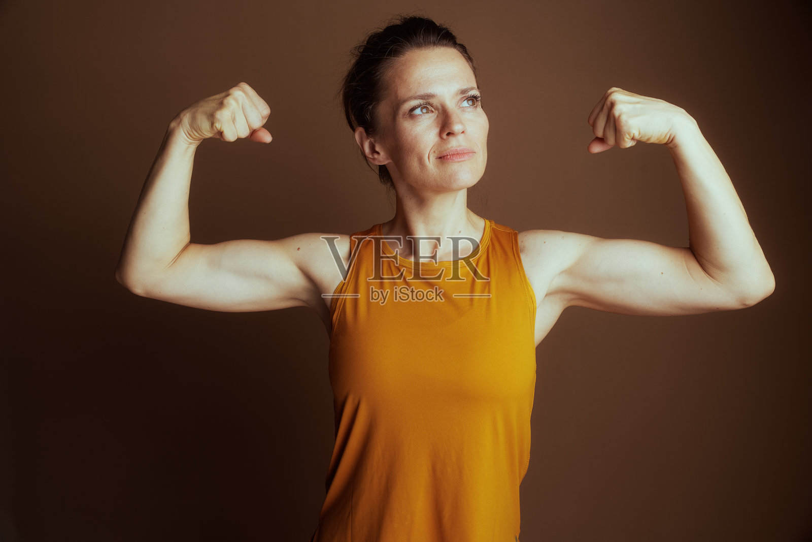 决心女性在黄色上衣中展示肱二头肌照片摄影图片