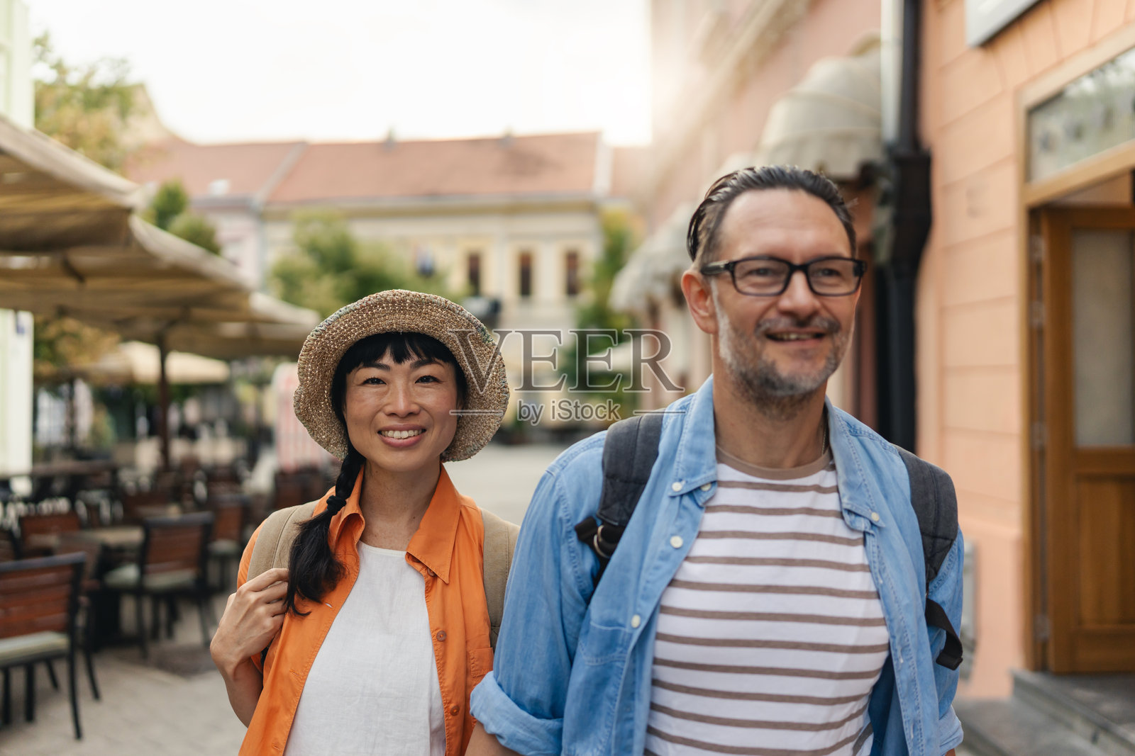 四十多岁的游客手牵手走在迷人的城市街道上，享受着观光、爱情和共同的旅行。照片摄影图片