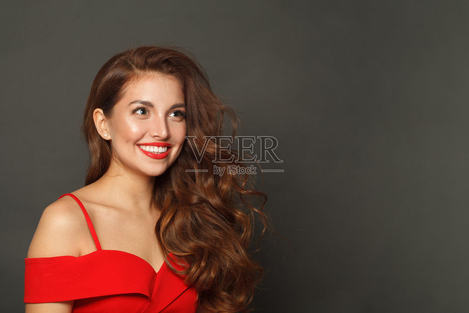 光泽肌肤、波浪发型和红唇妆的快乐时尚女模特，背景为黑色照片摄影图片