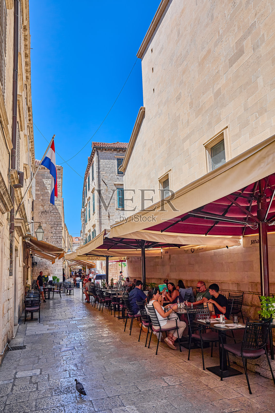 游客们在克罗地亚欧洲杜布罗夫尼克老城中心，大理石铺就的主干道--斯ग्राहक拉敦（Stradun，也称Placa）及其附近街道的餐厅和咖啡馆里悠闲地漫步和用餐。照片摄影图片
