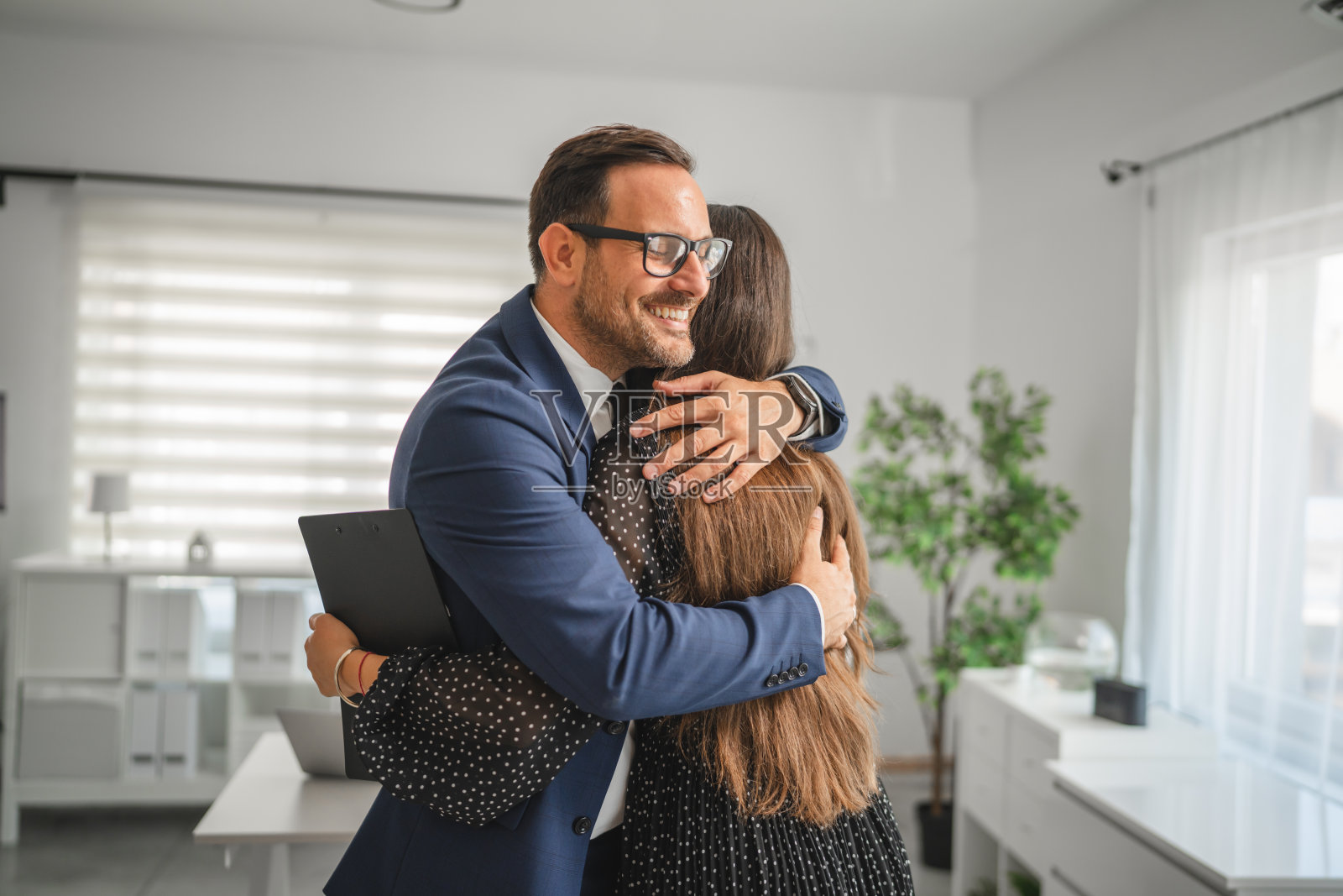 办公室里，商业伙伴们拥抱庆祝成功。照片摄影图片