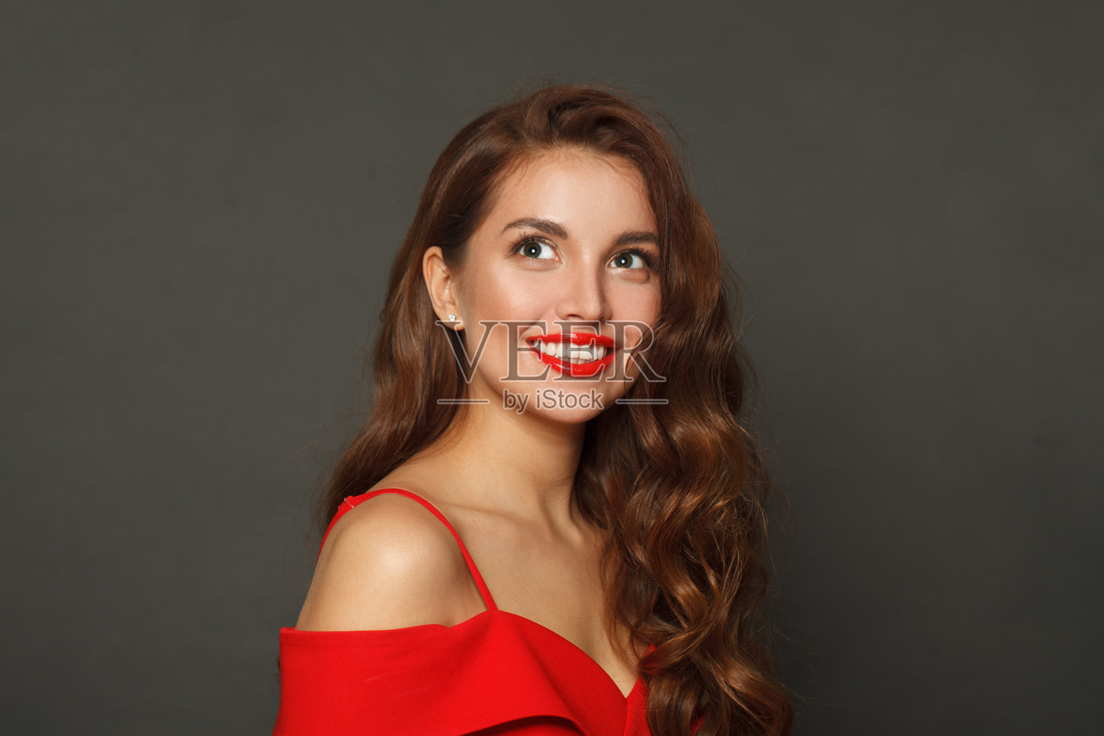 一位留着棕色卷发、时尚妆容、红唇的微笑金发女郎，背景为黑色。照片摄影图片