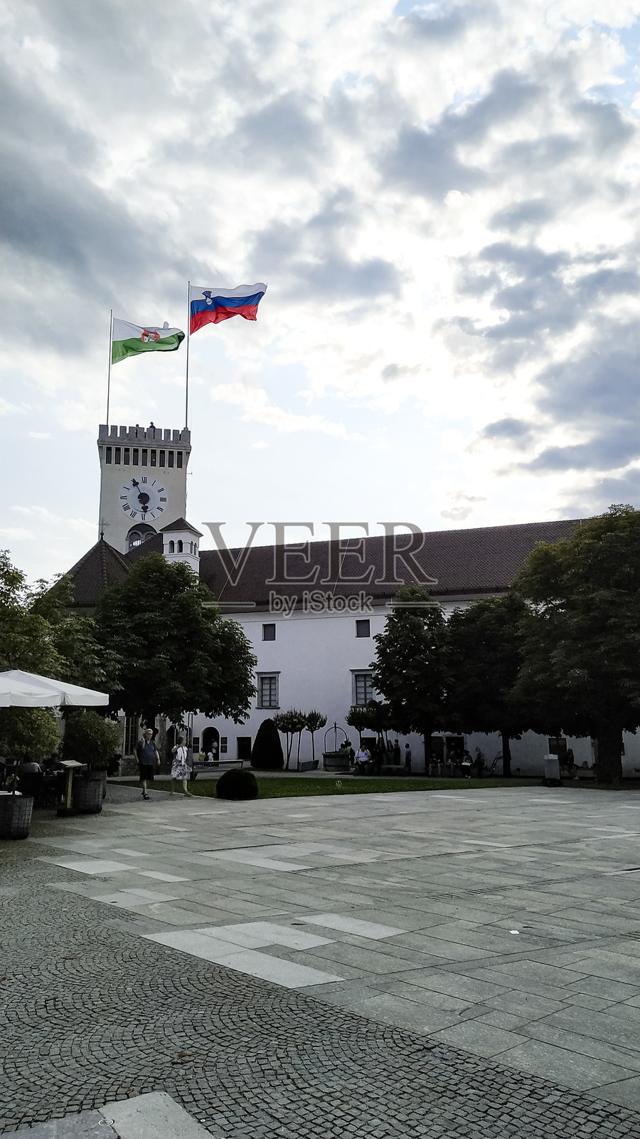 多云天空下，公共广场上飘扬着旗帜的历史建筑照片摄影图片