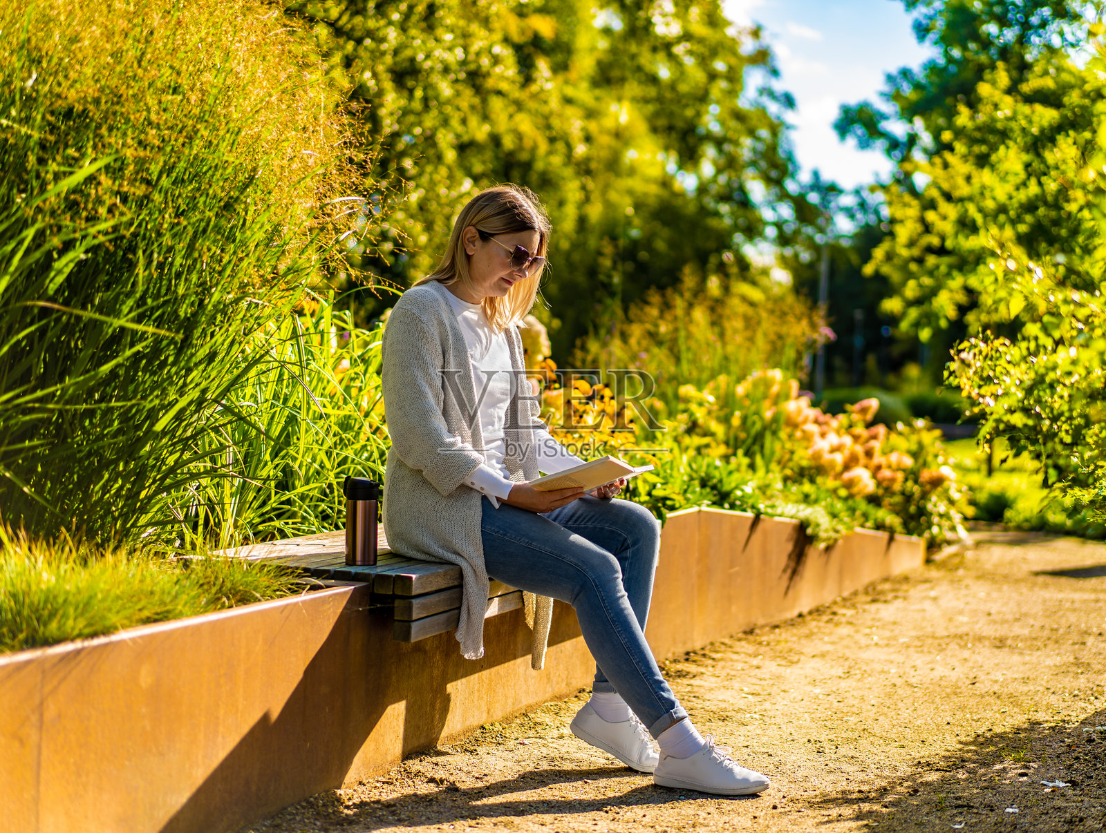 一位成熟美丽的女士坐在城市公园的长椅上读书。照片摄影图片