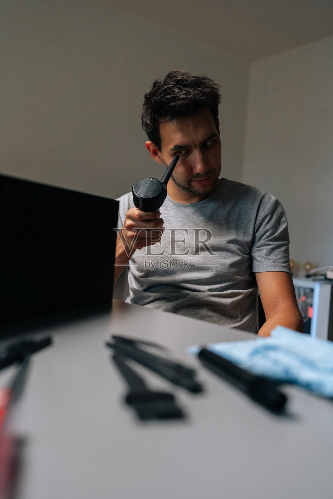 一名技术人员在清洁电脑零件时，竖构图肖像，检查小型真空吸尘器，以确保最佳性能和功能。照片摄影图片