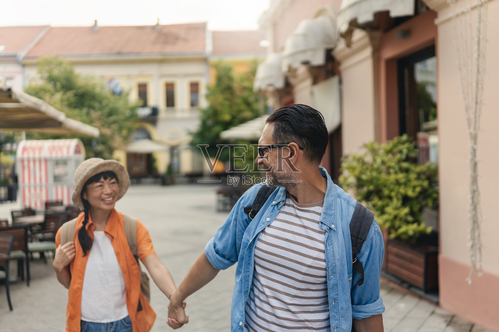 四十多岁的快乐游客手牵手漫步于迷人的城市街道，享受着旅行、爱情和共同观光照片摄影图片
