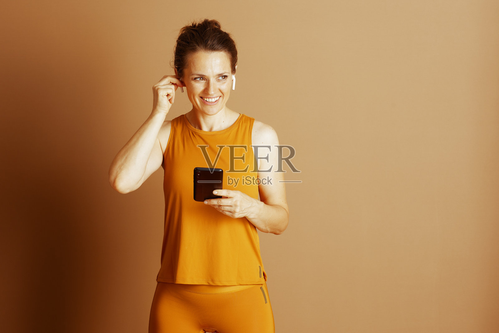 戴着耳机的女子，手持手机，准备开始锻炼照片摄影图片