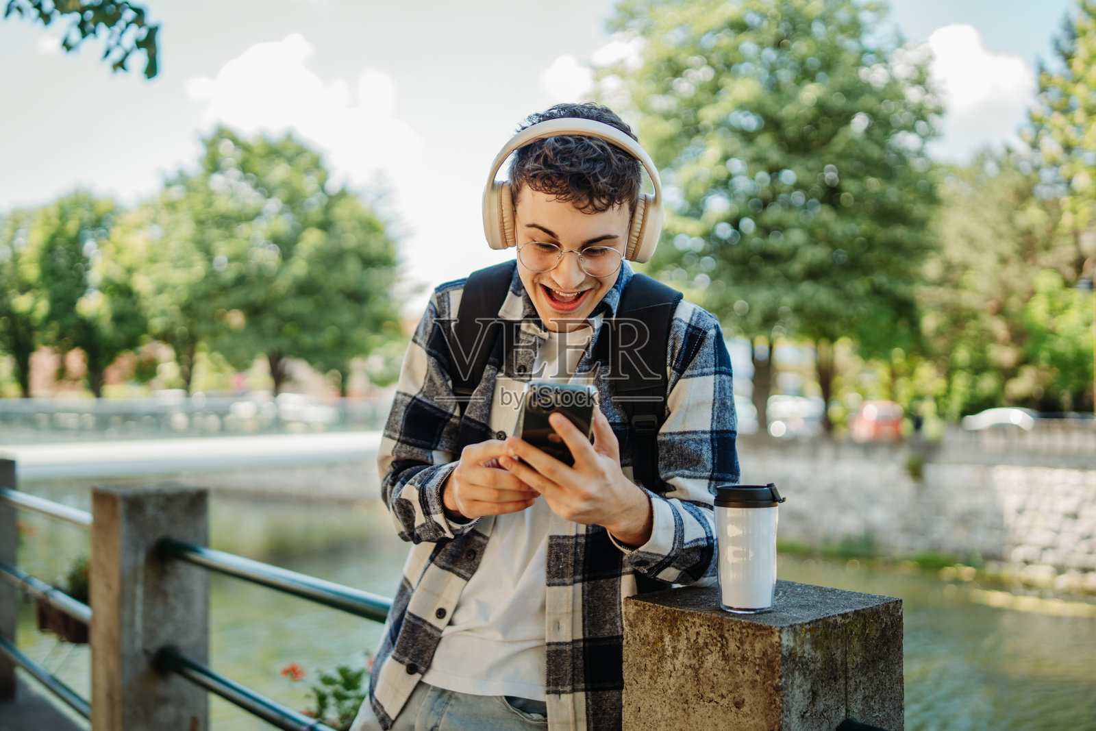 年轻的高加索男性学生正在使用智能手机，面带微笑。照片摄影图片