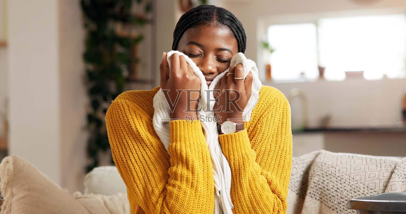 主妇在春季大扫除时，在家中享受衣物散发的芳香，进行家政清洁。这位快乐舒适的女士在客厅里，享受着家务活和织物柔顺剂的香味。照片摄影图片