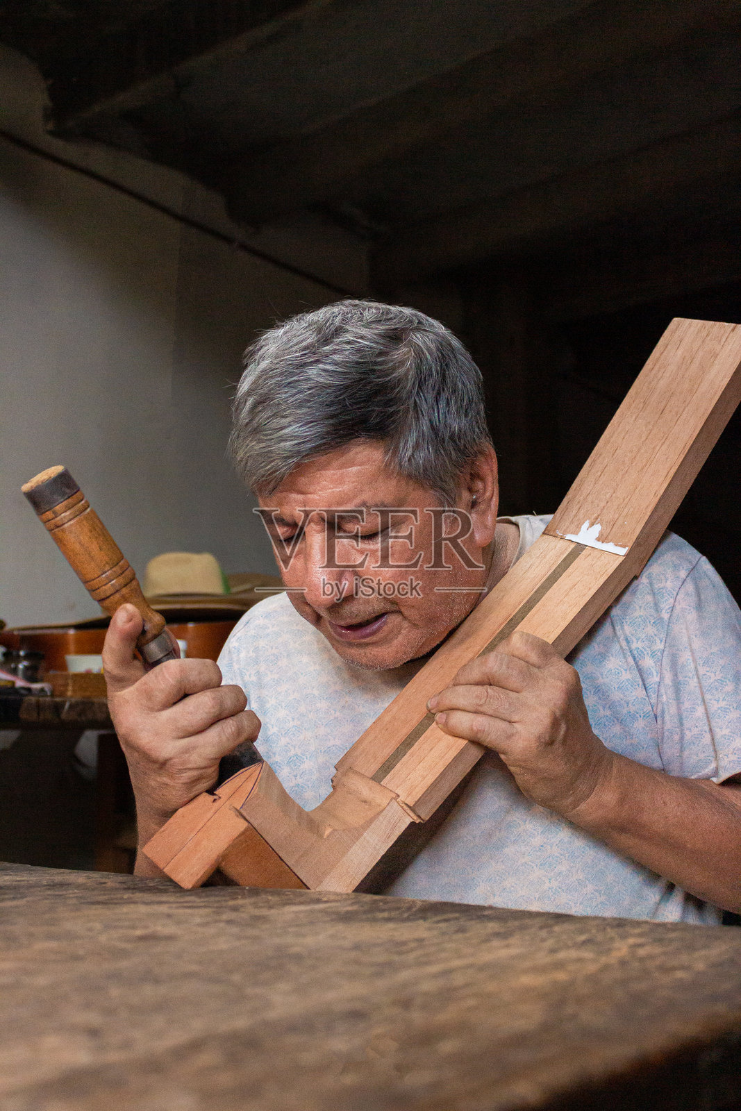 一位制琴师正在打磨一块用于制作原声吉他的木材照片摄影图片