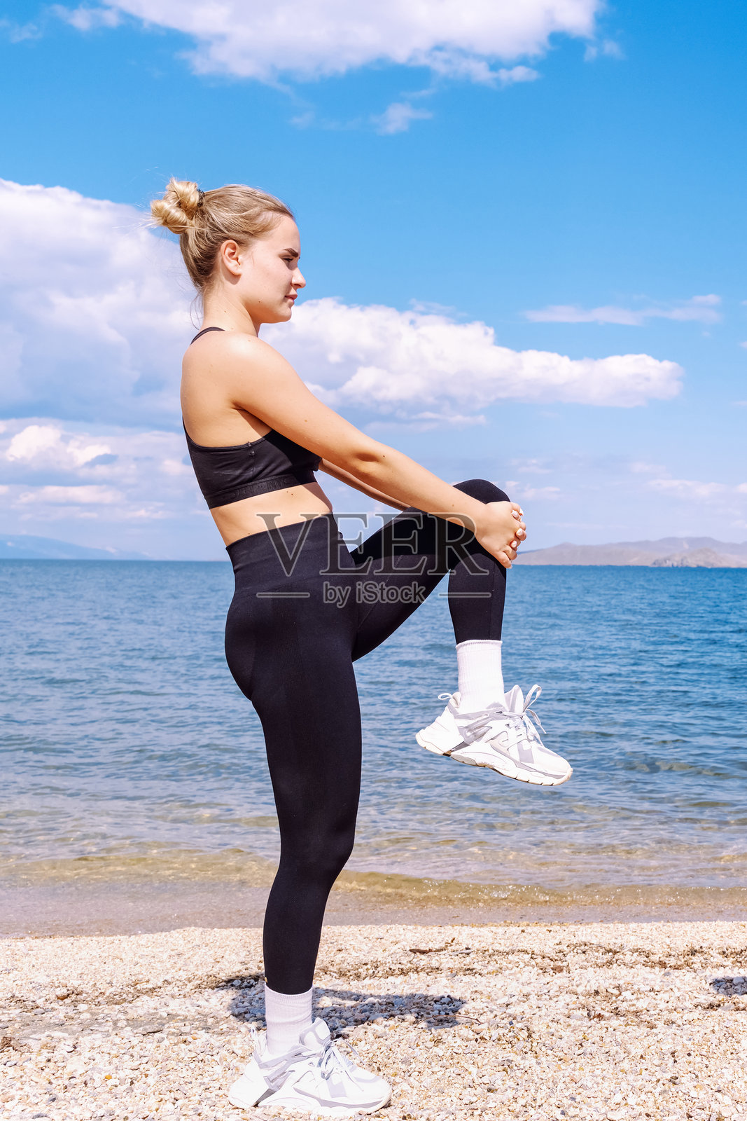 年轻女孩在晴朗蓝天下于海边水边锻炼照片摄影图片