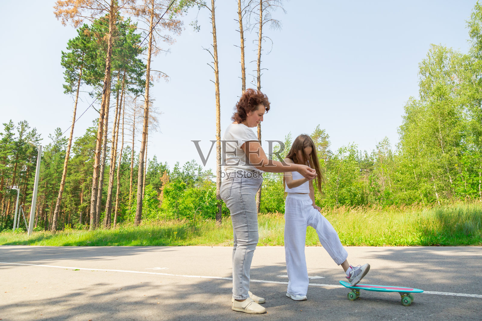祖孙二人，一位活跃快乐的祖母和孙女，在森林里玩滑板，共享欢乐时光。照片摄影图片
