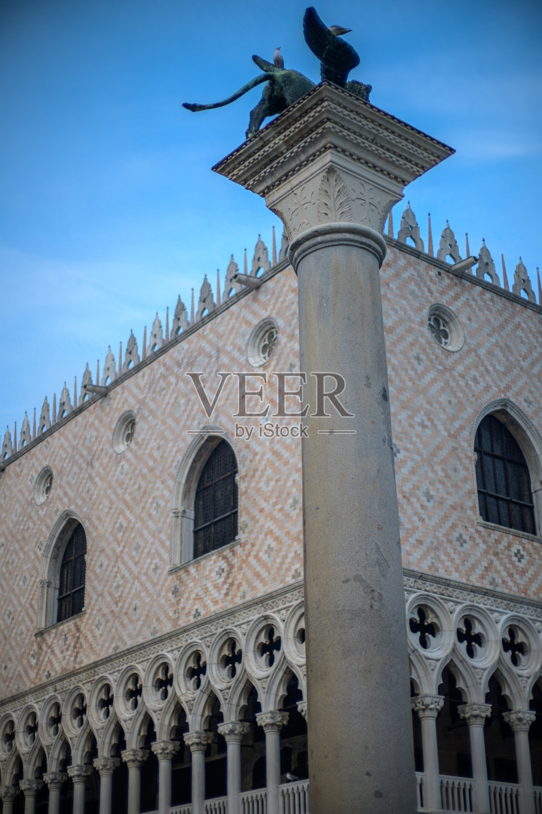 威尼斯圣马克广场上方石柱上的有翼雄狮雕像，背后是总督宫照片摄影图片
