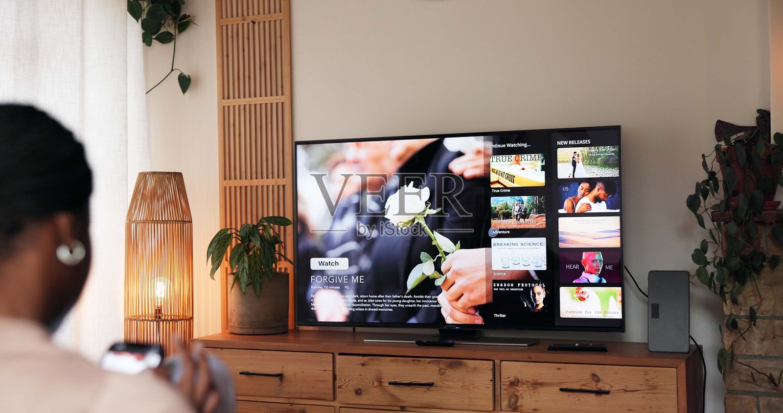 电视屏幕，周末女子在客厅放松观看电影、影片或节目。在家中，她做出选择，享受娱乐，并为在线流媒体订阅系列片做出决定。照片摄影图片