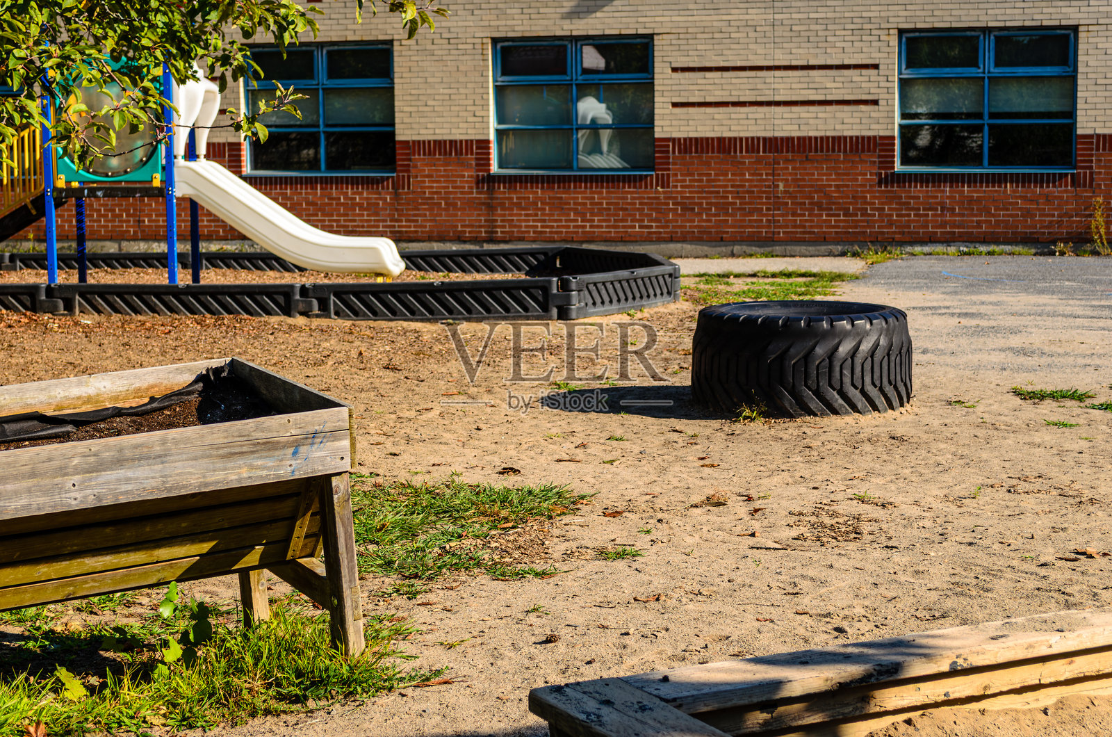 满是沙子、废弃旧轮胎和位于边缘的白色滑梯的游乐场照片摄影图片