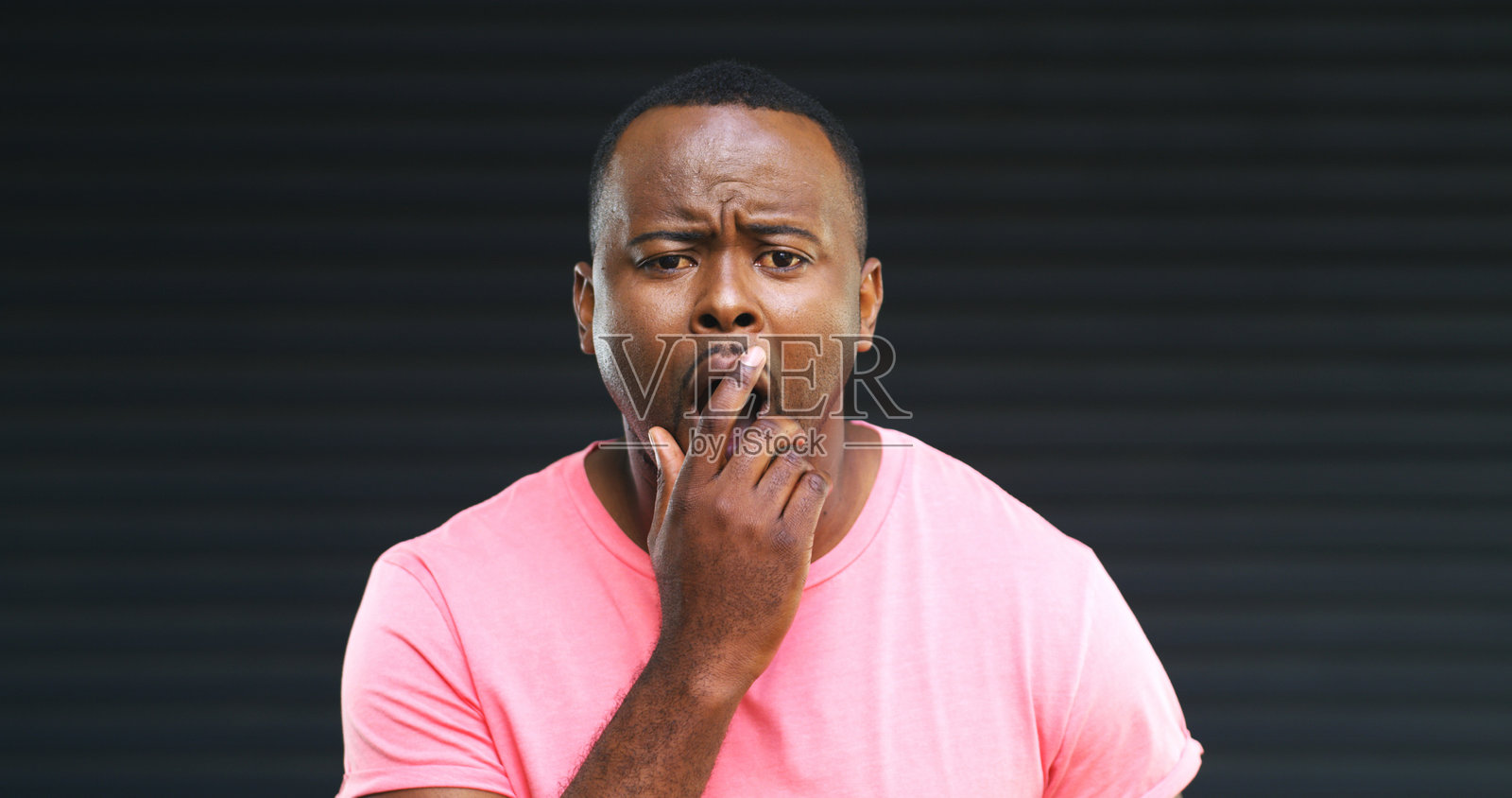 疲惫男士在工作室打哈欠，面带倦容，背景为灰色。他显得精力不足、筋疲力尽，脸上带着睡意、懒惰或无聊的表情，如同表情符号一般，人物为黑人模特，留有空间（用于文字添加）照片摄影图片