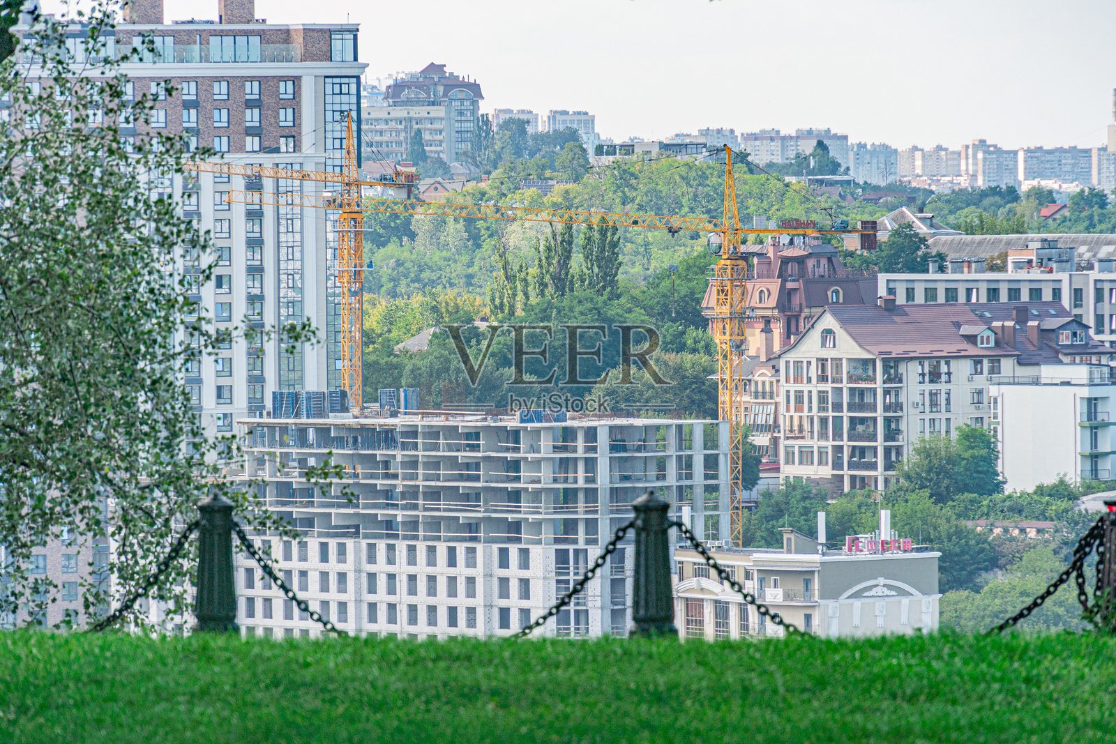 从高处俯瞰充满活力的城市景观，以黄色起重机和各种色彩缤纷的建筑为主，图中混合了住宅公寓和商业街区。照片摄影图片