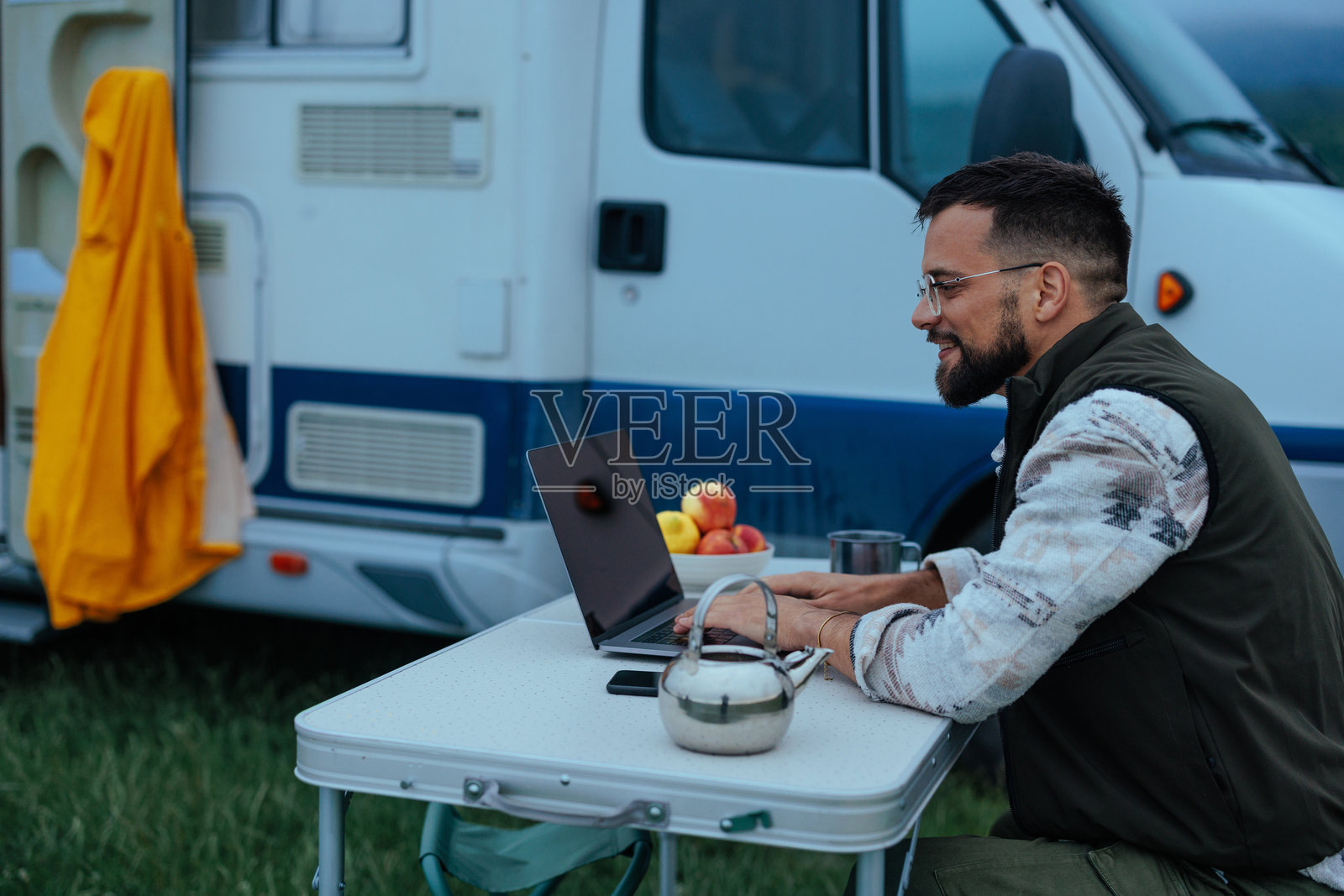 男人坐在露营车旁用笔记本电脑打字照片摄影图片