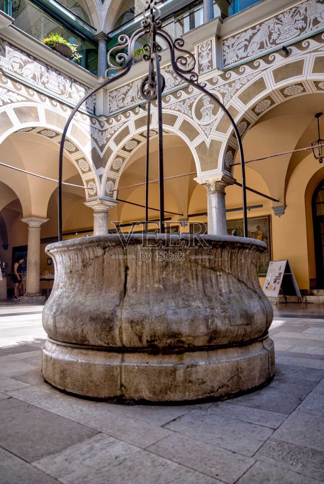 市中心旧市政厅的室内庭院，展示了饱经风霜的石墙、中央水井以及玻璃屋顶下的锻铁阳台。照片摄影图片