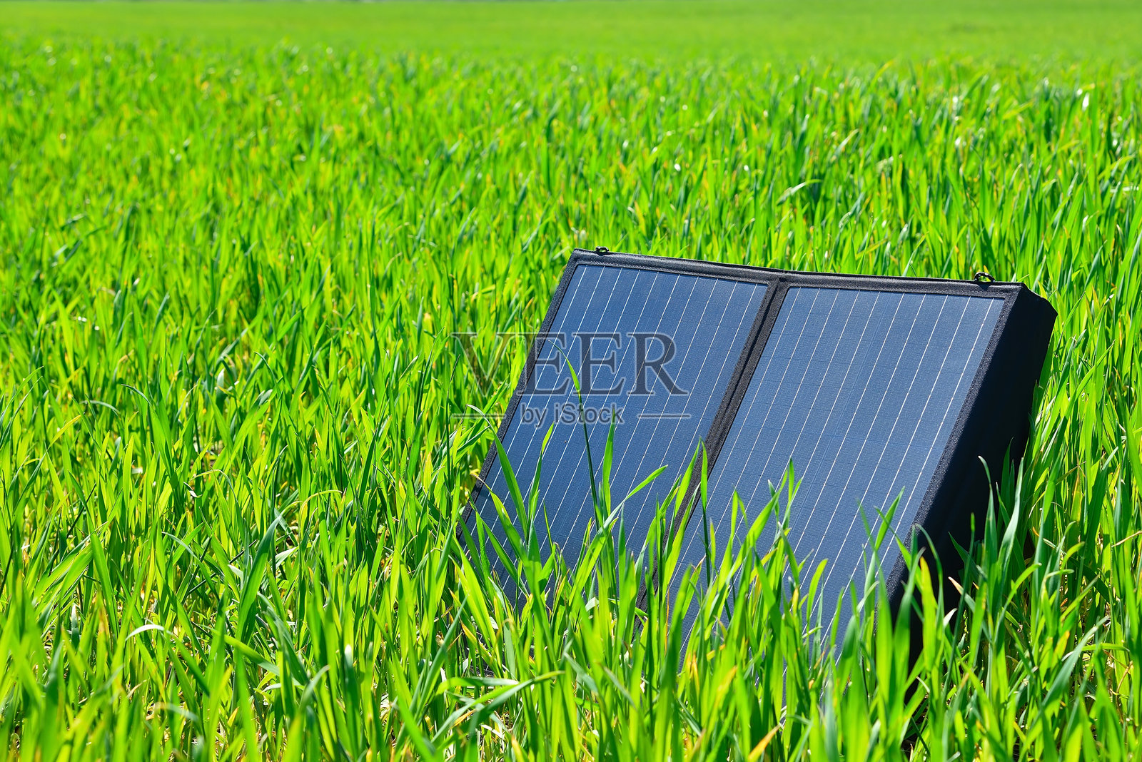 便携式太阳能电池板放在绿草地上。照片摄影图片