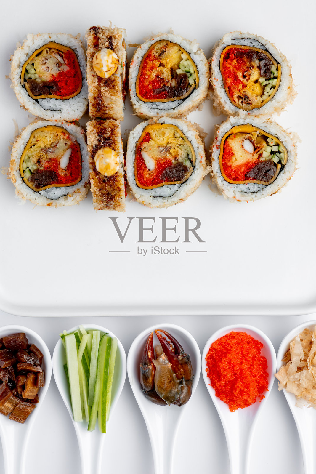 白底上面放着鳗鱼、蟹肉和鱼子酱的寿司卷，独立拍摄照片摄影图片