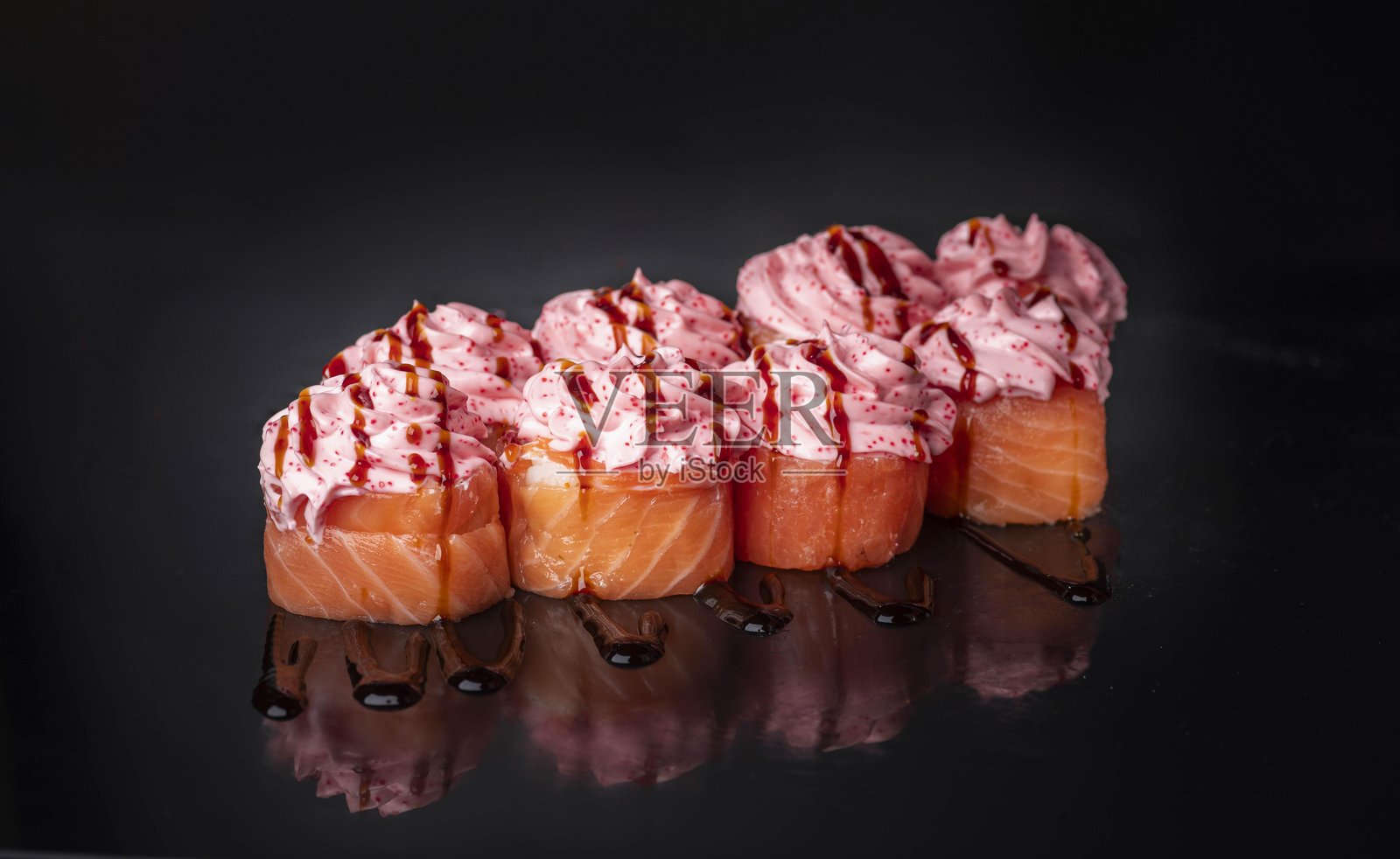 黑背景上的一组三文鱼军舰寿司，配有粉色奶油酱、鱼籽配料和酱油淋酱，概念为日式料理餐厅菜单上的海鲜佳肴亚洲美食寿司卷。照片摄影图片