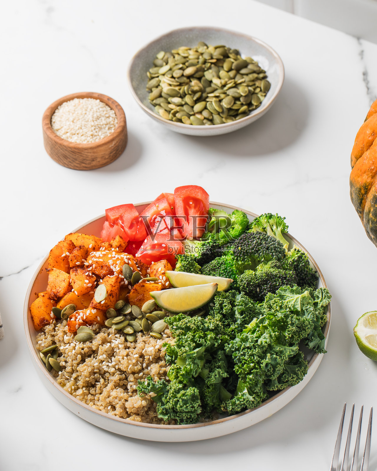 色彩鲜艳的纯素佛陀碗，配有藜麦、烤蔬菜和新鲜绿叶蔬菜。素食食谱。照片摄影图片