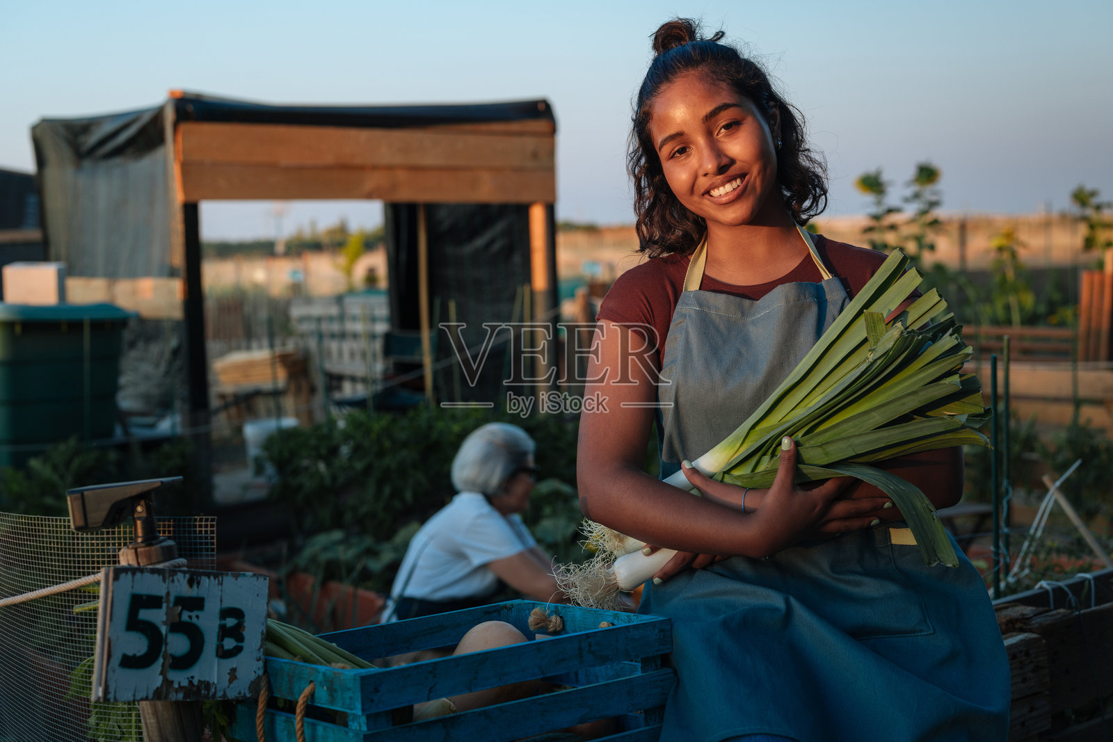 年轻的女农夫在社区花园里拿着新鲜的韭葱照片摄影图片