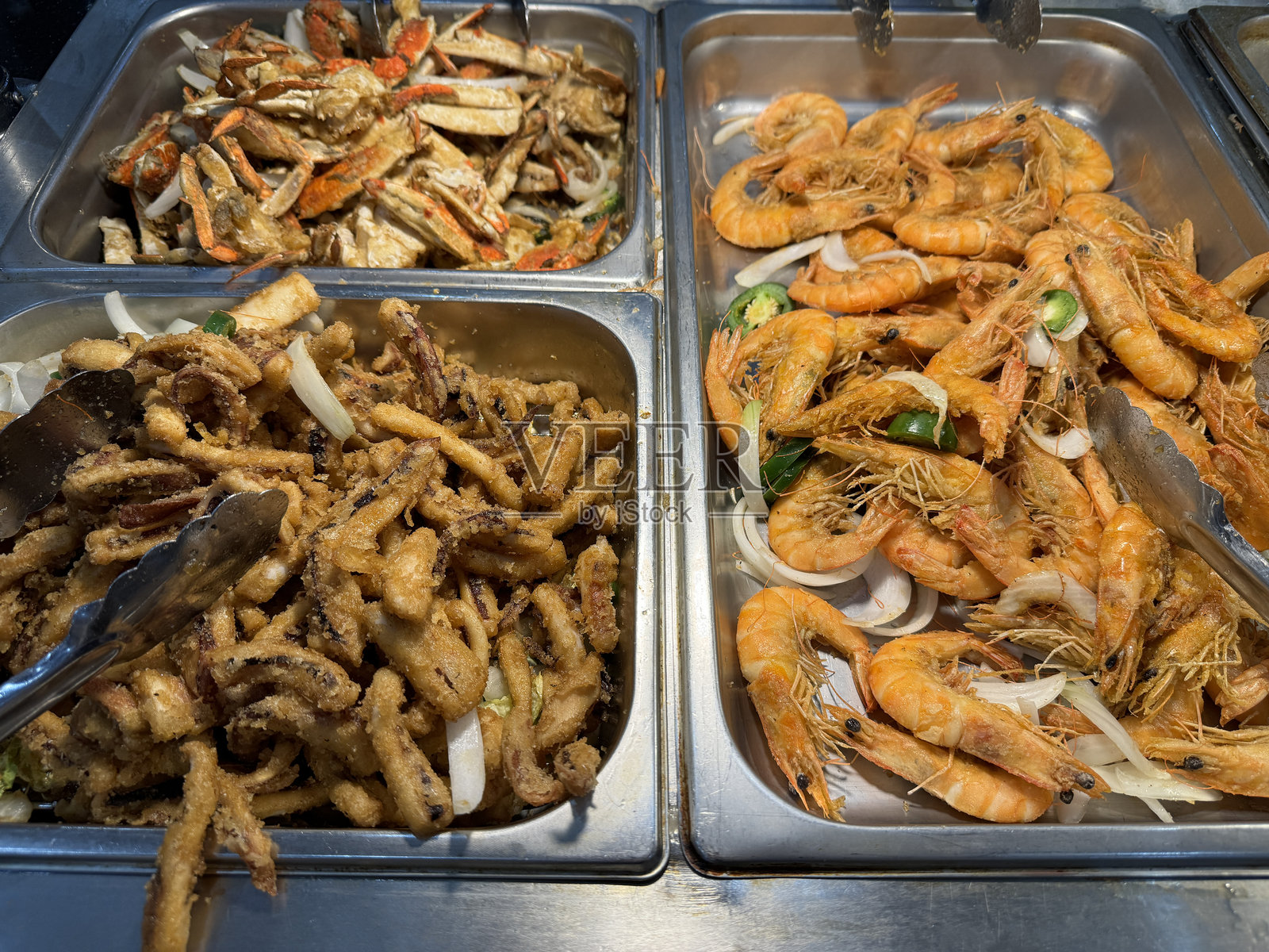 摆满炸鱿鱼圈、熟虾和调味蟹腿的自助海鲜盛宴照片摄影图片