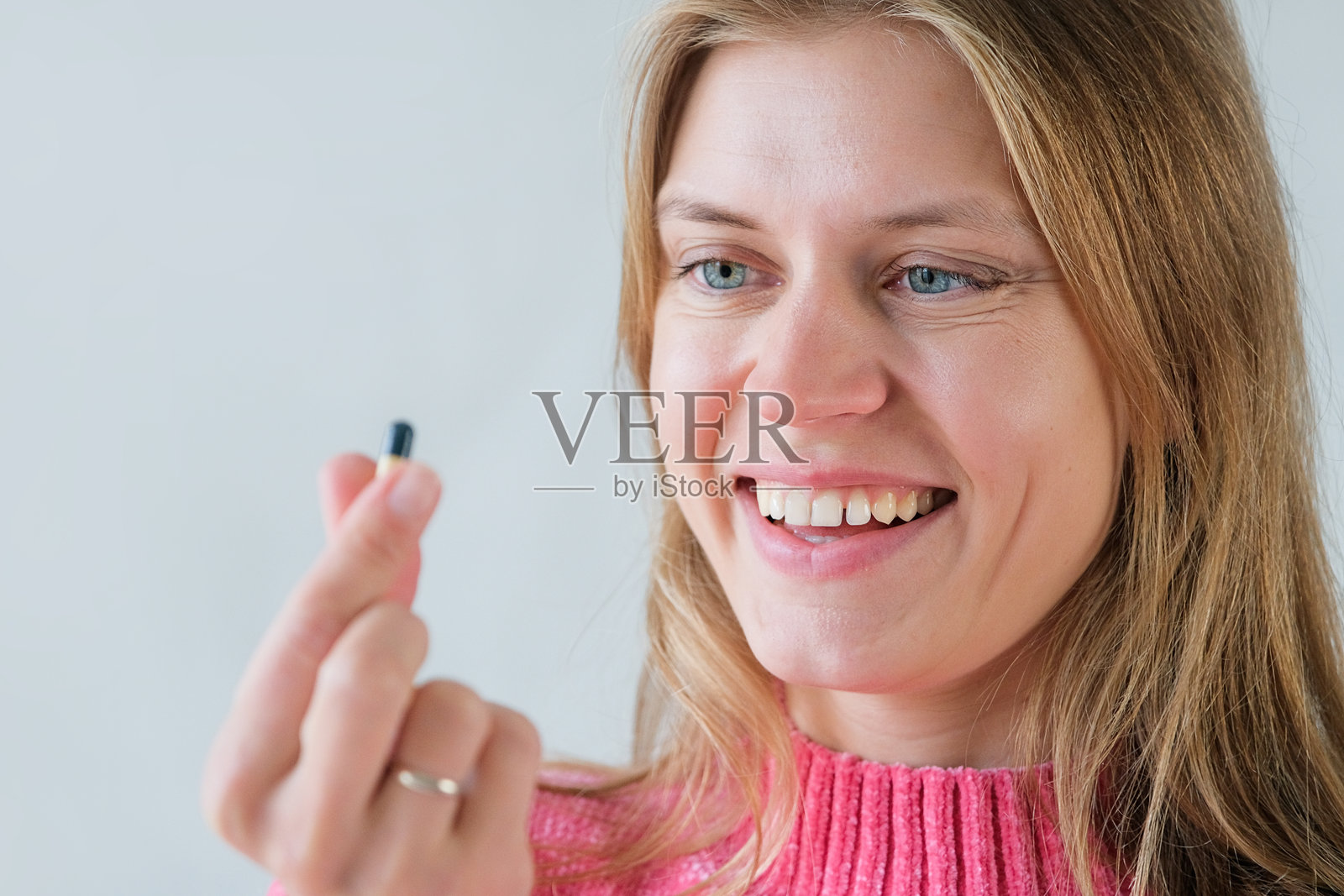 一名女子独自服用药丸，背景为灰色照片摄影图片