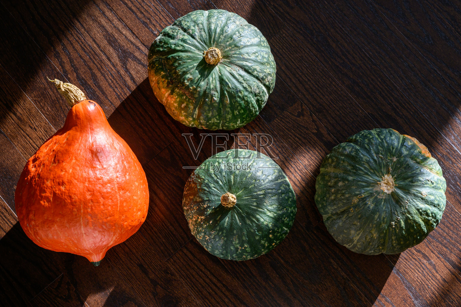 阳光下的橙色哈伯德南瓜和日本南瓜，置于木地板和白色背景上照片摄影图片