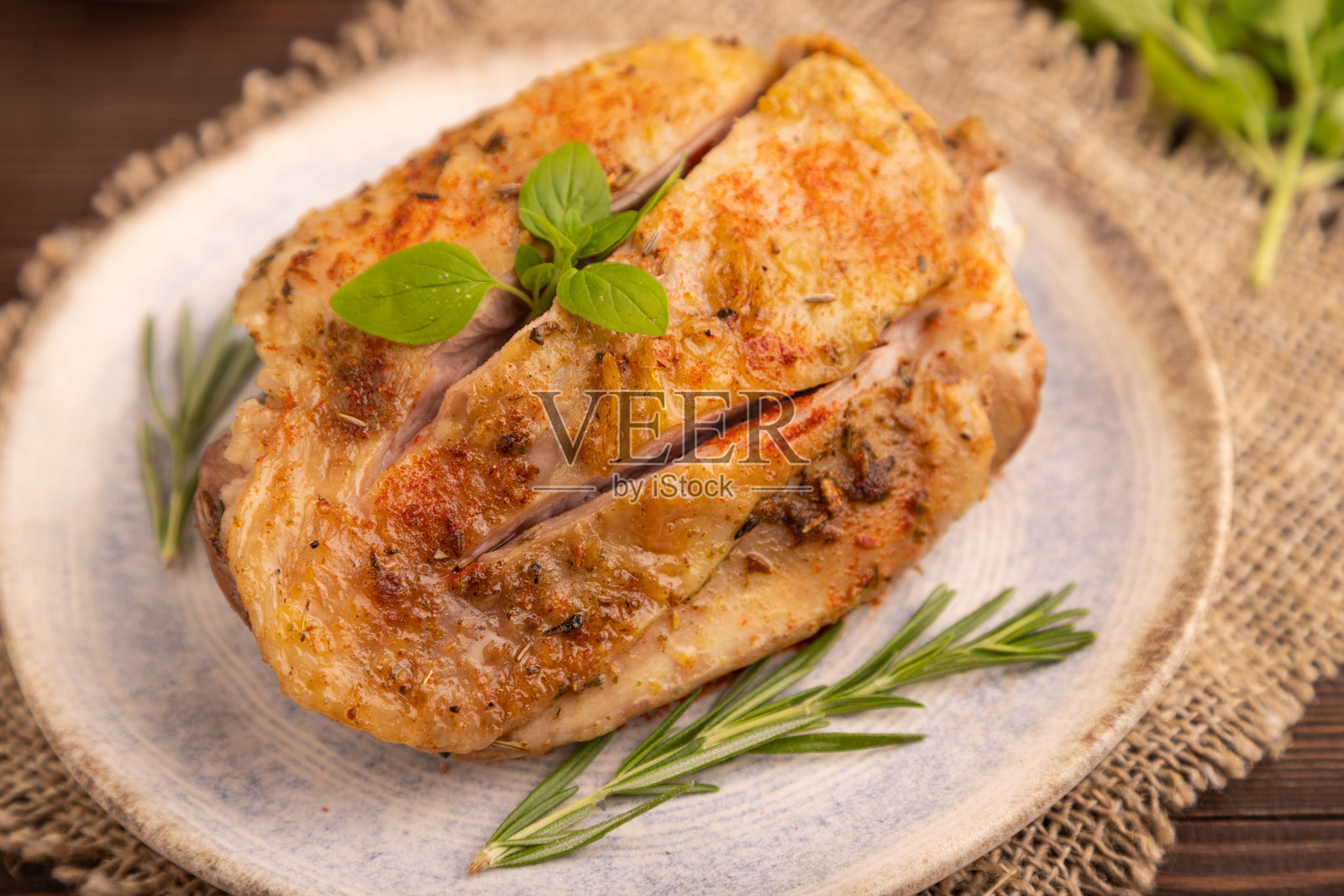 盘子里放着炸火鸡腿，上面撒着香料，背景是棕色的木头和亚麻布。侧面视图，特写，选择性聚焦。照片摄影图片