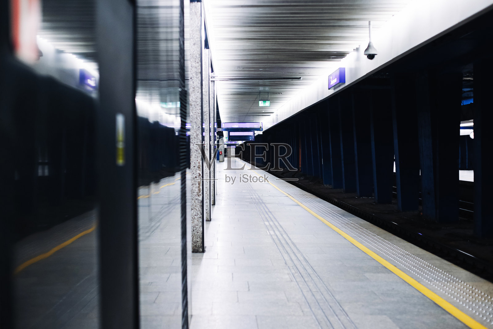 夜晚空无一人的地铁站台。带有黄线的地下车站。玻璃墙上的倒影。现代化的地铁内部建筑。照片摄影图片