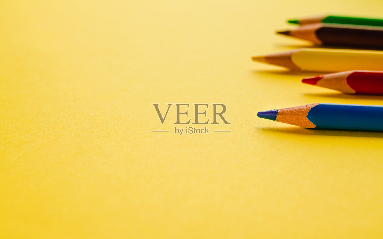 五彩的木质铅笔整齐地排列在明亮的黄绿色背景上，留有空白的复制空间，可用于文字、设计或创意项目。照片摄影图片