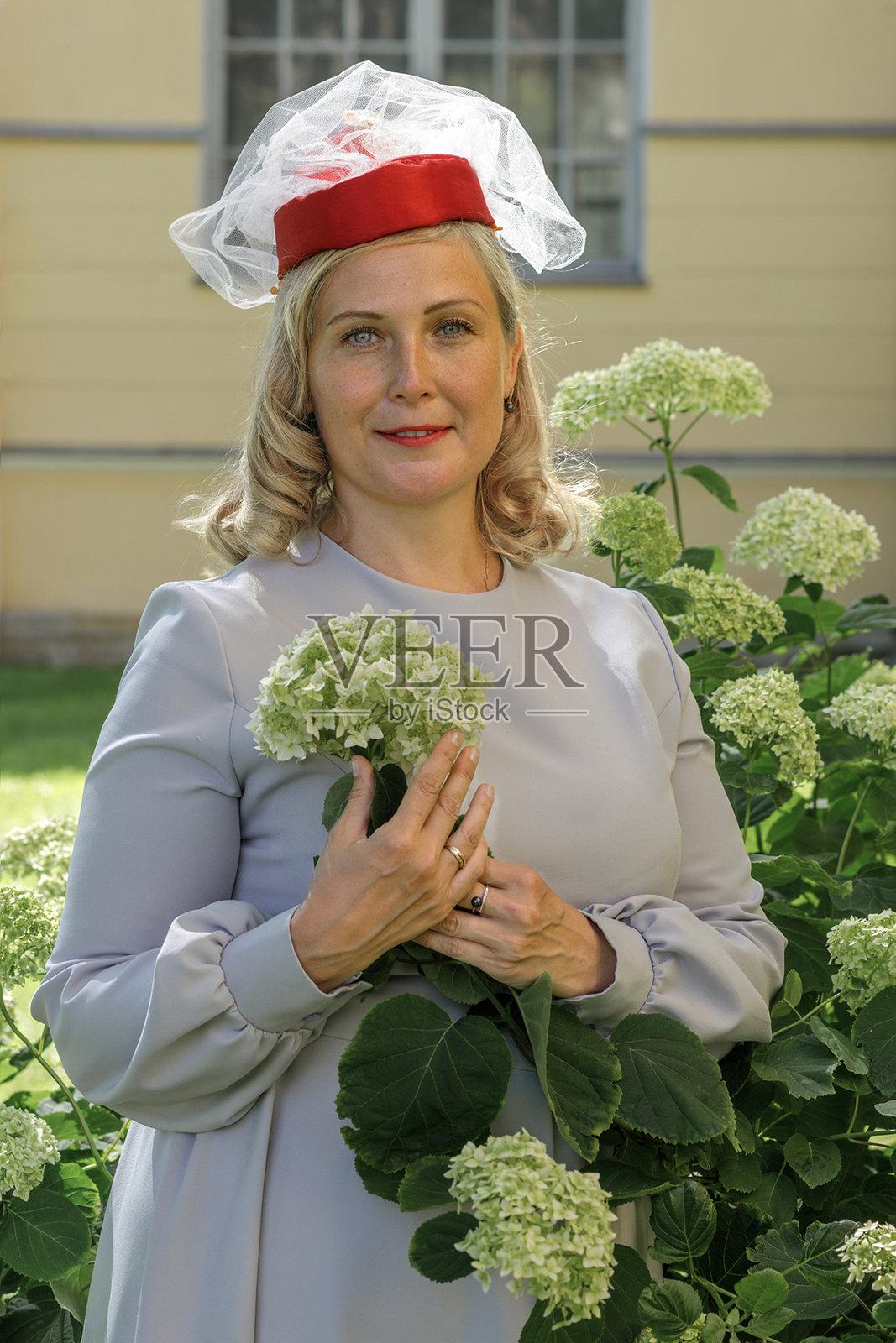 身穿复古红帽和蓝裙的年轻女子在夏日公园里散步。照片摄影图片