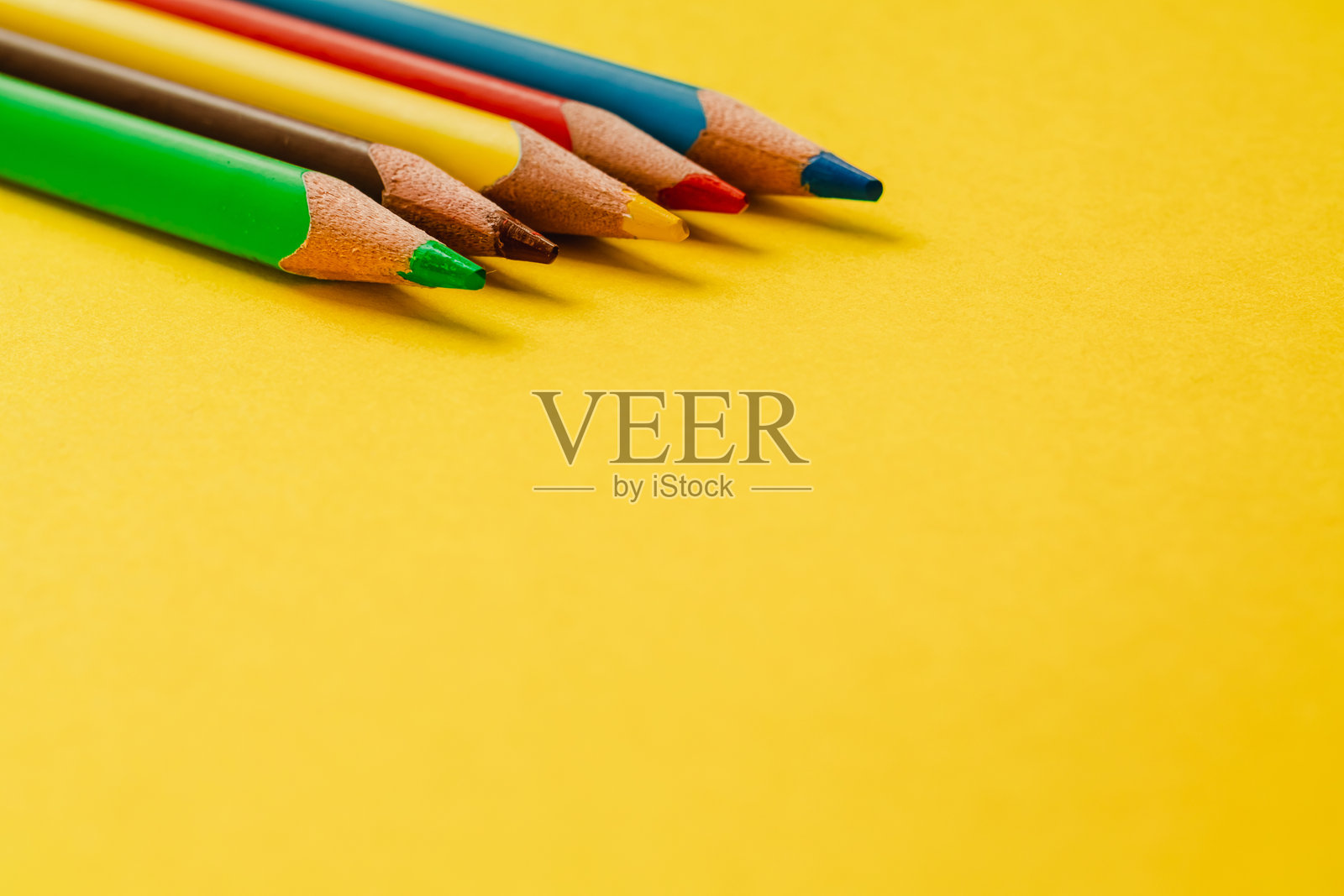 彩色木质铅笔整齐地排列在明亮的黄绿色背景上，留有空白的复制空间，可用于文本、设计或创意项目。照片摄影图片