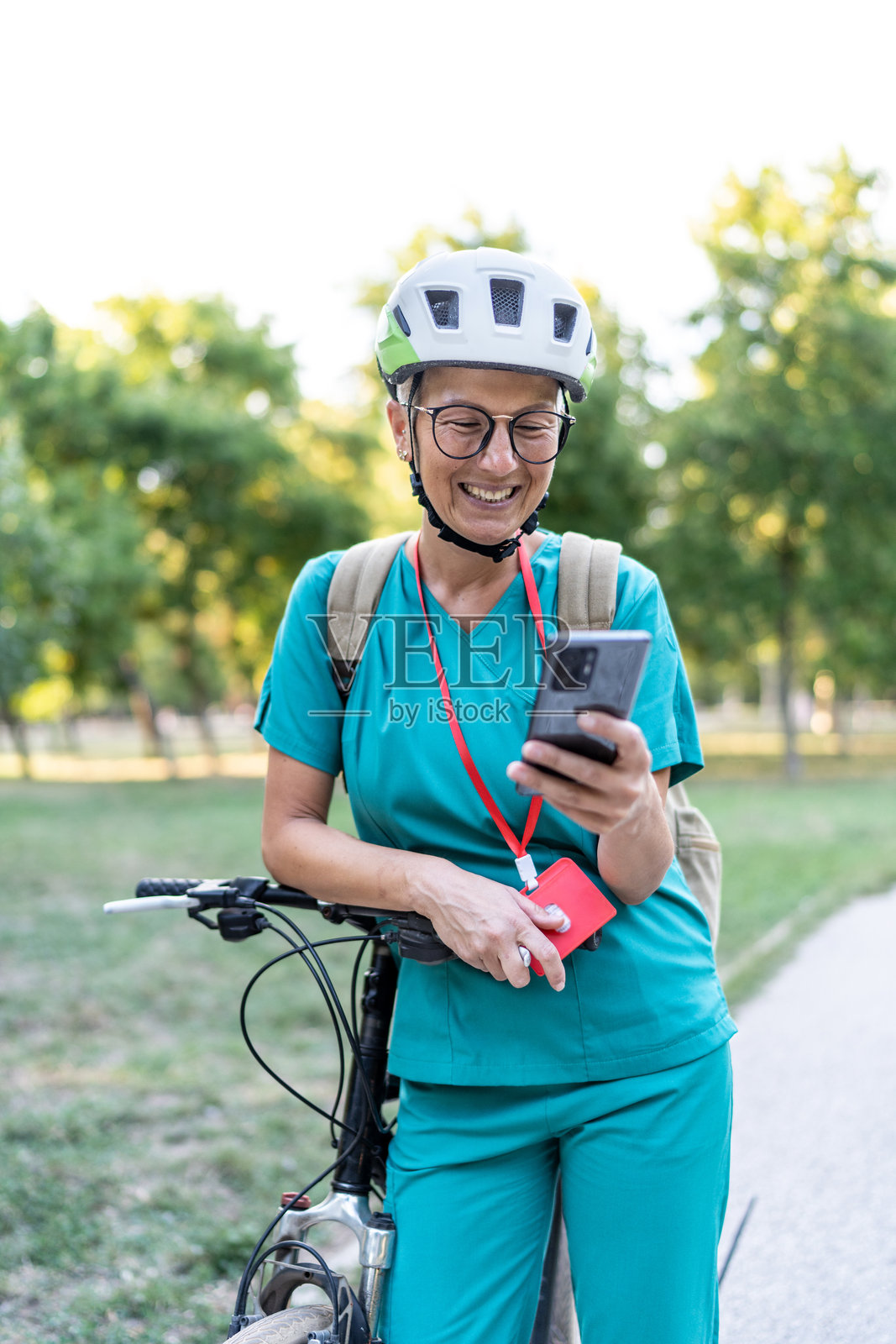 女护士骑自行车上班，查看智能手机照片摄影图片
