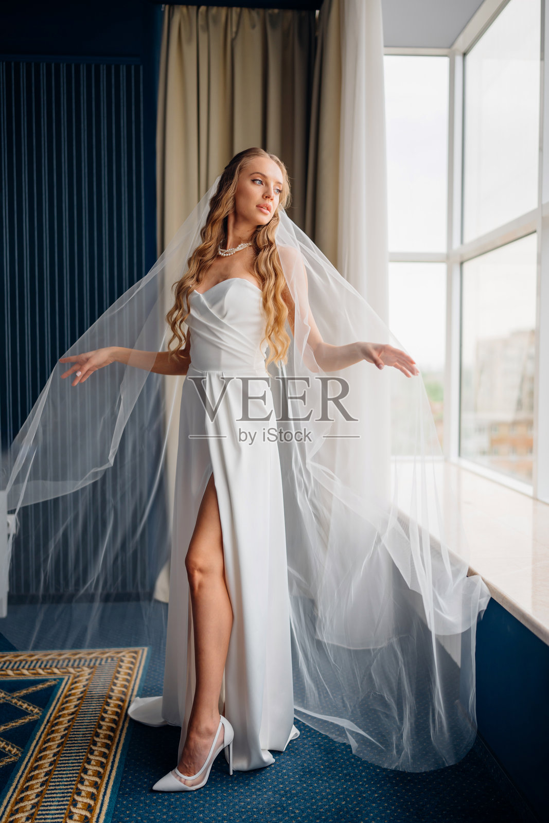 新娘站在窗边。简约优雅的婚纱。照片摄影图片