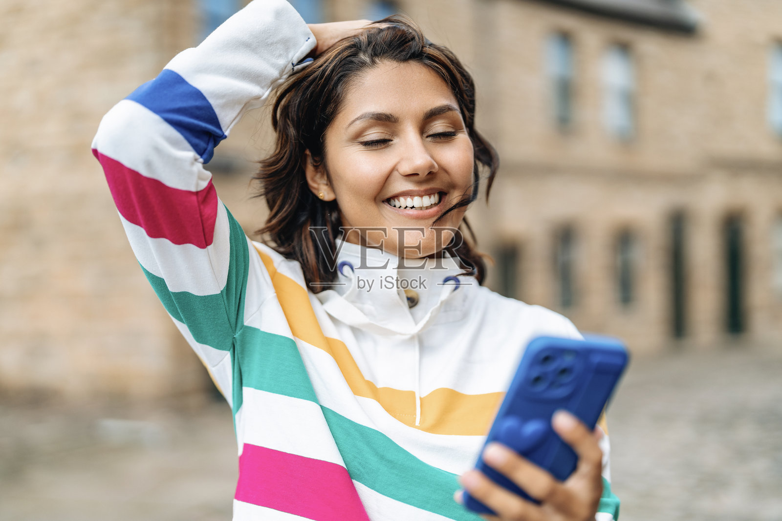 一位女士开心地笑着，看着她的智能手机，站在迷人的欧洲城市中照片摄影图片