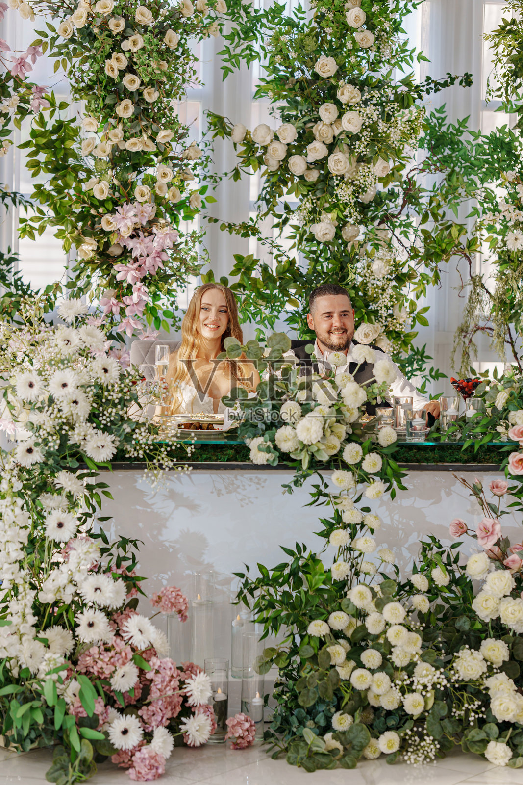 新婚夫妇在装饰着许多鲜花的新人桌旁照片摄影图片