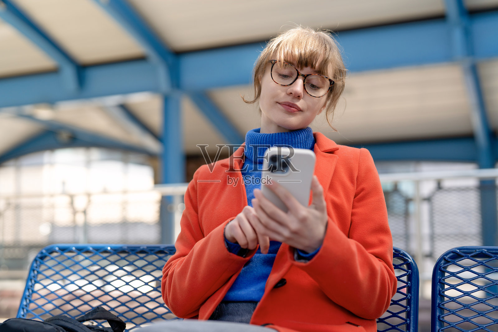 一位年轻女子下午在车站等火车时，正忙于看手机。照片摄影图片