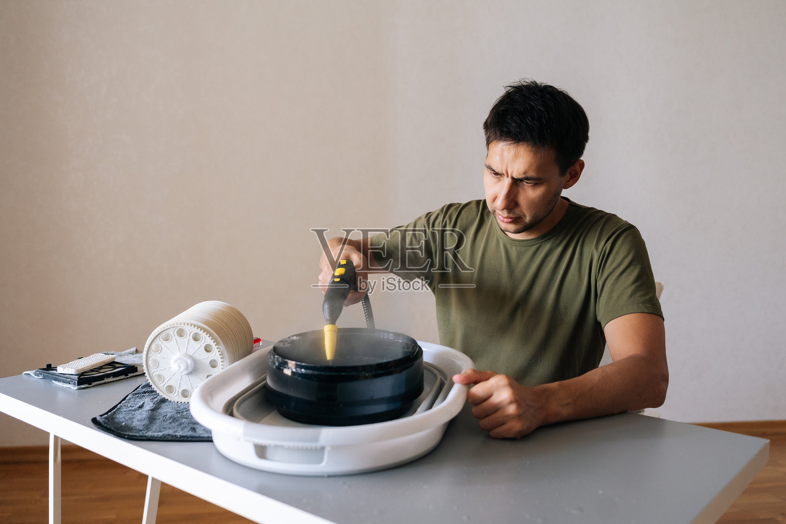 家庭主妇男性肖像，使用蒸汽清洁器清洁空气加湿器滤网，进行维护以确保空气质量健康。照片摄影图片