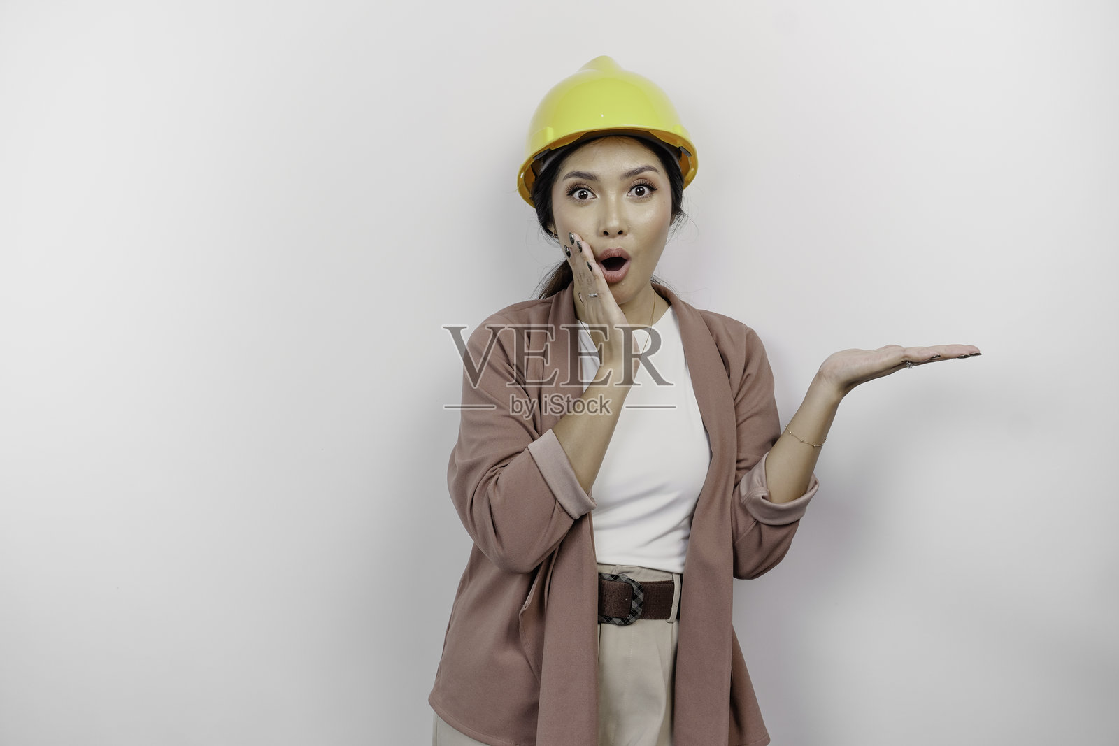 穿着安全头盔的亚洲女员工，吃惊地指向她旁边的复制空间。照片摄影图片