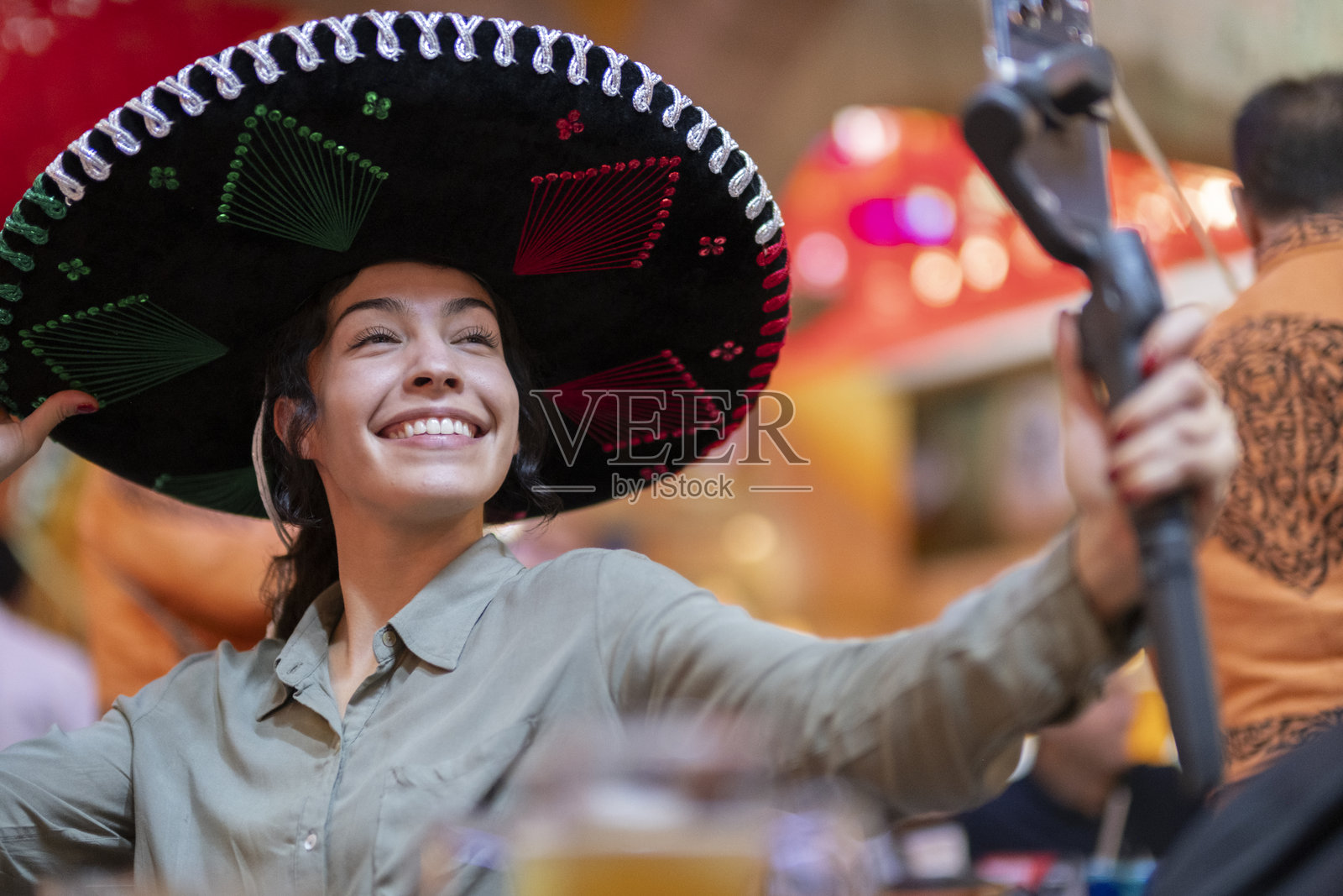 年轻的游客在墨西哥国庆节期间，穿着墨西哥国旗配色的查罗帽等传统服装，进行记录和写博客。照片摄影图片